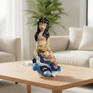 The Talavera Hub hand-painted mermaid figurine with floral tail, coral top, black hair, holding a yellow fish on blue waves.