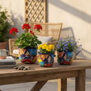 The Talavera Hub set of 3 colorful hand-painted ceramic flower pots with floral designs and blue rims.