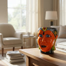 The Talavera Hub hand-painted orange ceramic face planter with blue eyes and colorful headdress. Folk art style.