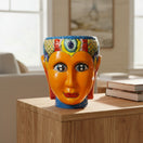 The Talavera Hub hand-painted Talavera face planter, orange ceramic with colorful headdress and blue base.