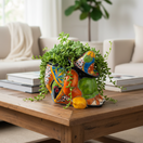 The Talavera Hub colorful ceramic planter shaped like a sleeping man in a sombrero, hand-painted with orange, blue, green, and red.