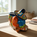 The Talavera Hub colorful ceramic planter shaped like a sleeping man in a sombrero, hand-painted with orange, blue, green, and red details.
