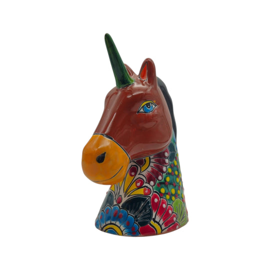Front view of a multicolor Talavera unicorn head figurine with red face and green horn